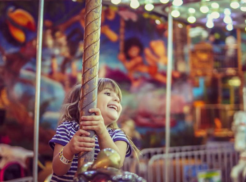 Happy little girl on a merry go round filled with joy