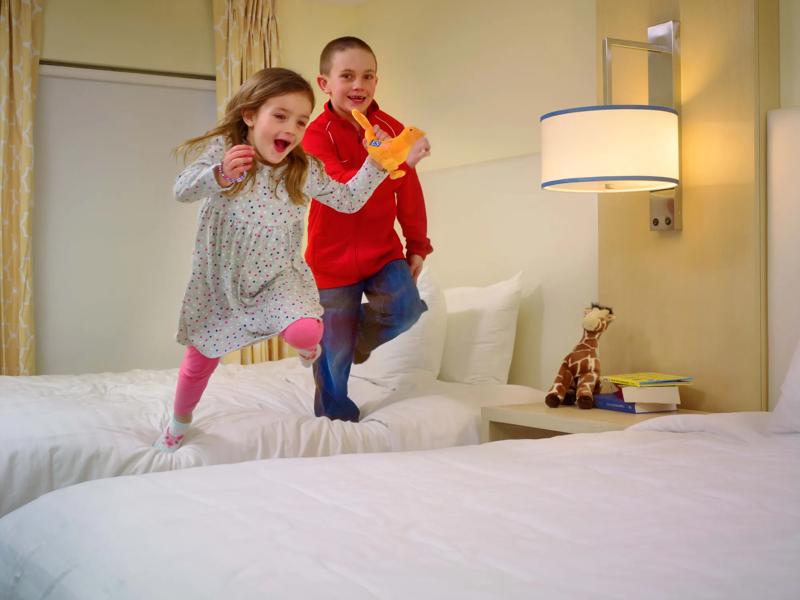 SES_Brand_AuburnHillsDetroit_Suite_TwoBedroom-DoubleBeds-WithKidsJumping-2 - 654CD1AA-6EB7-485B-8F93DFD243CCB0F7