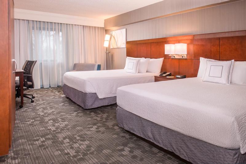Double room with two beds, nightstands, lounge chair, desk and rolling chair