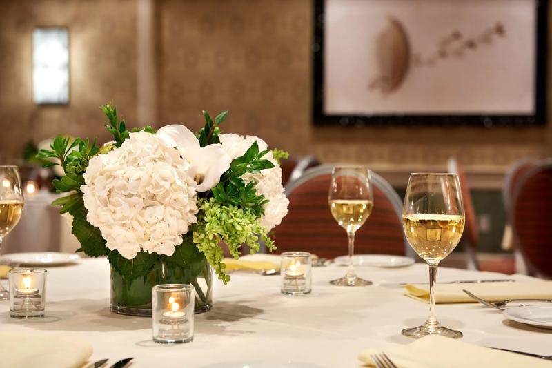 A close up of the flower bouquet center piece and dining table details during an event